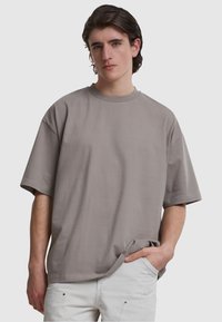 Tricou cu mânecă scurtă, lejer, de culoare gri mat, fabricat dintr-un material moale, cu guler rotund și fără modele vizibile.