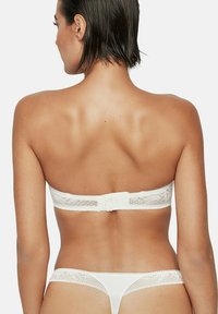 Soutien-gorge bandeau en dentelle blanche avec un string assorti, présentant une texture lisse, des bords en dentelle délicate et une fermeture à crochets dans le dos.