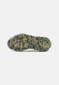 Suola di una scarpa con battistrada simile a tacche in colori mimetici, dotata di punte e motivi circolari per garantire aderenza.