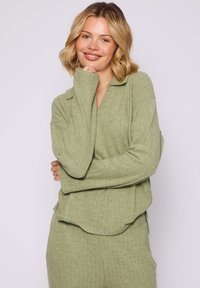 Pull en maille côtelée vert clair avec un col et une coupe décontractée. Texture douce, manches longues et ourlet arrondi.