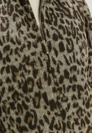 Leopardprint fleecejack met een ritssluiting, voorzien van een gestructureerd beige en bruin patroon, en een zachte, warme uitstraling.