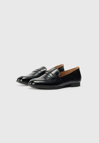 Mocassins en cuir noir avec un bout arrondi, une sangle décorative sur le devant, une finition lisse et une semelle basse et plate.