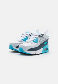 Le sneakers Nike Air Max presentano una parte superiore bianca e grigia, dettagli blu, tessuto testurizzato, lacci e un'unità d'aria visibile nella suola.