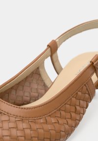 Ταμπά δερμάτινο παπούτσι slingback με μπεζ λουριά και επενδεδυμένο πάτο, με κοντινή όψη που αναδεικνύει τις λεπτομερείς ραφές και την υφή.