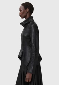 Schwarze Lederjacke mit hohem Kragen, taillierter Passform und asymmetrischem Saum. Glatte Textur mit seitlichem Reißverschluss.