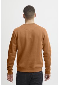 Sudadera marrón de cuello redondo con mangas largas, fabricada en un tejido suave, con puños y dobladillo acanalados. Diseño sencillo, sin patrones visibles.