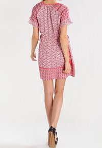 Růžové šaty s krátkým rukávem, zdobené květinovým vzorem, s přiléhavým pasem a volány na okrajích, s nařaseným zadním dílem a vrstveným lemem.