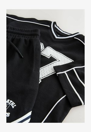 Maillot de sport noir et short assorti en tissu maille, avec des accents blancs et un grand motif de numéro. Taille élastique à cordon sur le short.