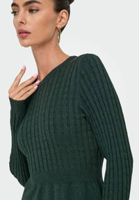 Ciemnozielony sweter z prążkowanej dzianiny z dekoltem w serek, ozdobiony textured kablami, z długimi rękawami, gładką tkaniną i dopasowaną talią.
