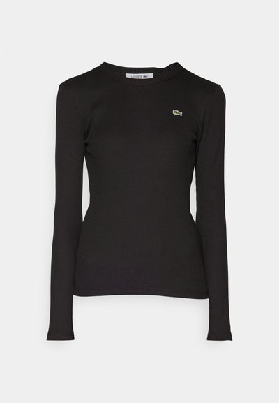 Chemise noire à manches longues en tissu côtelé avec un col rond et un logo vert brodé sur la poitrine gauche. Coupe ajustée.