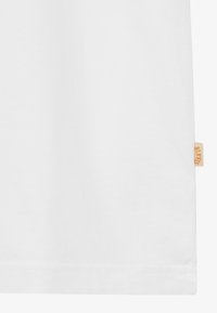 Balta medvilninė marškinė su minimalistiniu dizainu, turinti mažą oranžinę etiketę apatinėje siūlėje. Lygus tekstūros paviršius ir klasikinis įsiliejimas.