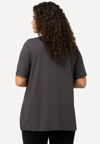 T-shirt grigia a maniche corte con vestibilità morbida e orlo curvo, realizzata in un tessuto morbido, con dettagli di cucitura discreti sulla schiena.