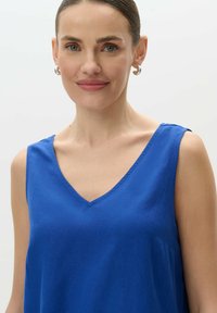 Plava bezrukavna majica s V-izrezom, izrađena od laganog materijala. Ima jednostavan dizajn i glatku teksturu, idealna za svakodnevno nošenje.