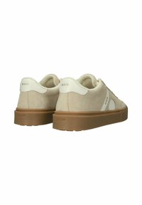 Beiget mokkanahkaiset tennarit, joissa valkoiset nahkaiset kantapääosat, kuminahkaiset pohjat ja "Blackstone"-brändäys kantapäässä ja sivuilla, kuvattuna takaa.