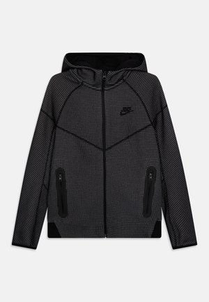 Czarna kurtka z kapturem na pełny zamek z drobnym białym wzorem w kratkę, logo Nike na piersi i zamykane na zamek boczne kieszenie.
