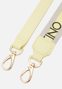 Limetkově žlutý popruh s hladkým povrchem, vybavený zlatými kovovými sponami a šedou částí s černým textem. Dvoubarevný design.