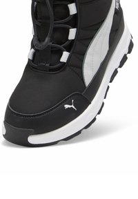 Svart sportskor med en slät tygöverdel, gummisula, snörningsdesign och grå accentpanel. Har en vit logotyp på sidan.