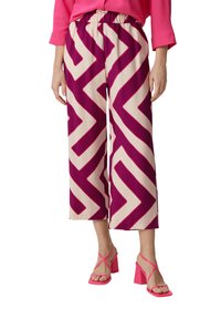 Spodnie o szerokich nogawkach w fioletowo-beżowy wzór w zygzaki, z elastycznym pasem, połączone z różowymi sandałami na słupku z paskami.