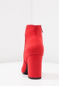Czerwone zamszowe botki si�ęgające kostki na wysokim słupku. Posiadają zamek błyskawiczny z tyłu oraz gładką fakturę z okrągłym noskiem.
