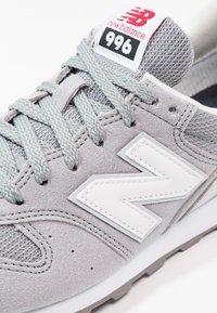 Šedé tenisky New Balance 996 s nubukovým svrškem, texturovanou síťovinou, bílým podpisovým logem "N" a šedými tkaničkami s polstrovaným jazykem.