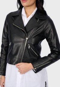 Černá kožená krátká bunda s klopovým límcem, asymetrickým zipem a dvěma předními kapsami na zip. Hladká textura.