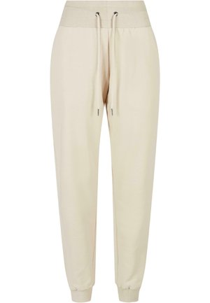Lyse beige joggebukser laget av mykt stoff, med ribbestrikket midje, snor og elastiske mansjetter ved ankelen.