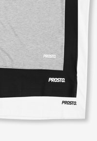 T-shirt w kolorze szarym i czarnym z blokami kolorów z białymi akcentami, z logo "PROSTO." nadrukowanym na materiale. Bawełnowy, krótki rękaw.
