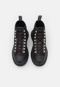 Zapatillas altas negras de cuero liso, con ojales plateados, cordones rojos y negros, y una suela de goma texturizada.