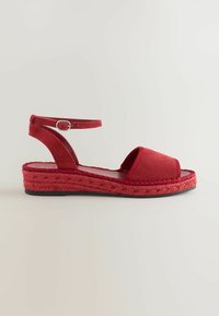 Rode espadrille sandalen met een zachte stofafwerking, open neus en enkelbandje. Heeft een gevlochten jute tussenzool en platte rubberen zool.