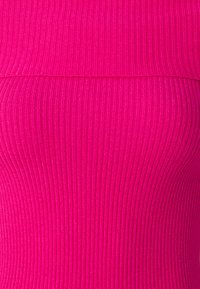 Le haut fuchsia côtelé présente un tissu texturé avec des lignes verticales, mettant en valeur un design ajusté et un col superposé. Aucune quincaillerie ou accent visible.