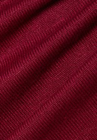 Bordowa tkanina o teksturowanym wzorze prążkowanym, z widocznymi drobnymi ściegami i delikatnym połyskiem, układająca się w miękkie, faliste fałdy.