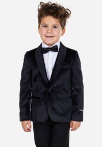 Blazer de terciopelo negro con solapas de satén, combinado con una camisa blanca y una pajarita negra. Presenta un corte ajustado y dos bolsillos frontales.