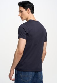 T-shirt blu navy a maniche corte con collo rotondo, realizzato in tessuto morbido, caratterizzato da una silhouette aderente e dettagli di cucitura minimi.