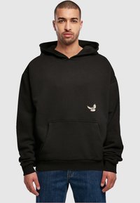 Sort hætte sweatshirt med en forb-pocket og broderet fuglegrafik på venstre side. Stof ser blødt ud med en afslappet pasform.