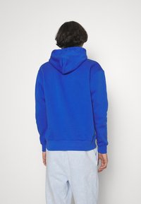 Blauer Kapuzenpullover aus weichem Material, mit einer vorderen Tasche, gerippten Bündchen und Saum sowie einer lockeren Passform. Rückansicht gezeigt.