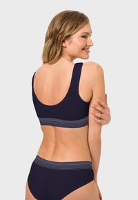 Marineblaues Badeanzug-Set bestehend aus einem Sport-BH und Bikini-Hosen mit gestreiften Akzenten. Weiches, elastisches Material mit glatter Textur.