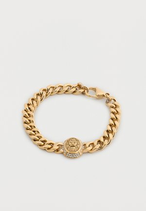 Armband met goudkleurige ketting en een ronde bedel met een leeuwenkop, versierd met kleine heldere edelstenen en een sluiting met kreeftenklauw.