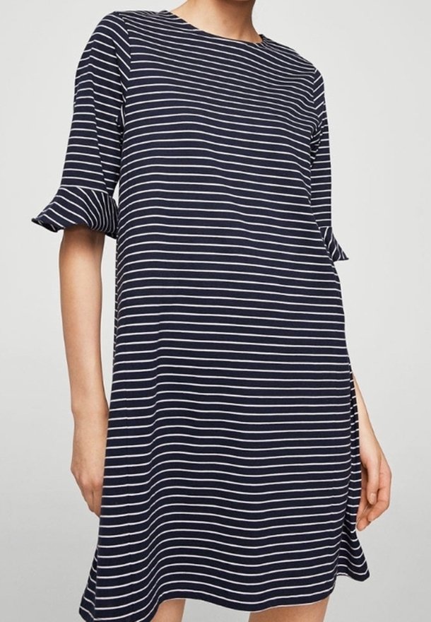 Femme portant une robe bleu marine avec de fines rayures horizontales blanches et des manches courtes ornées de volants.
