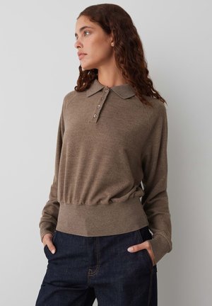 Pull polo marron à manches longues avec col et patte de boutonnage à cinq boutons, doté d'une taille ajustée et d'une texture douce, associé à un jean noir.