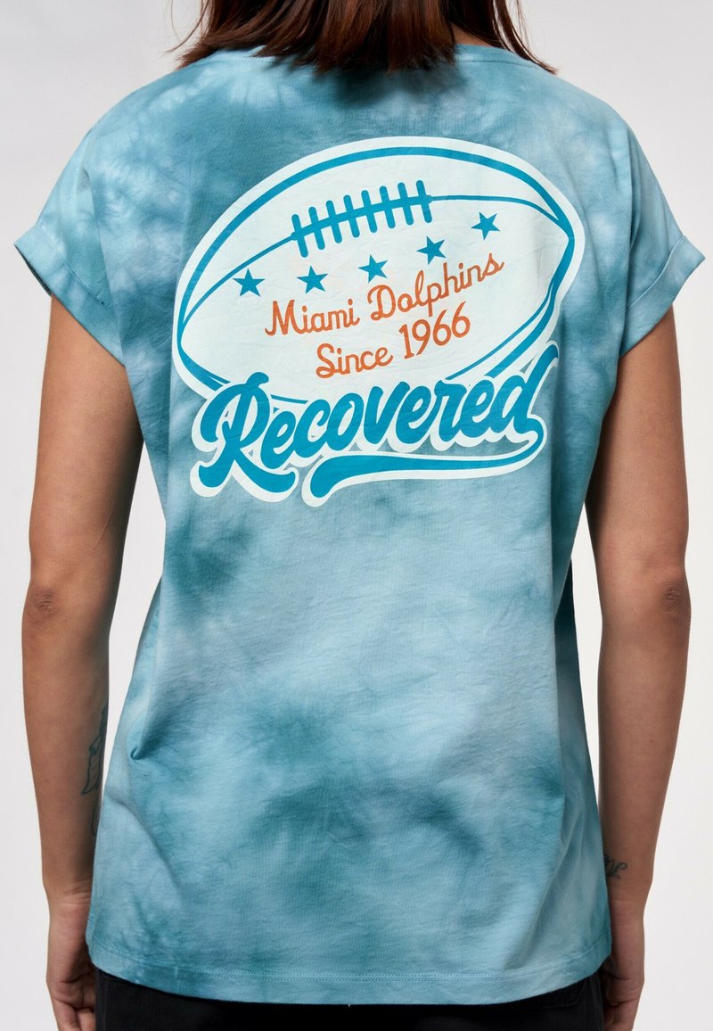 Kortärmad, tie-dye t-shirt i blå gradient. Har en vit fotbollsgraphic med orange och turkosa texter som säger "Miami Dolphins Sedan 1966."