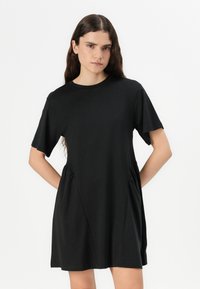Zwarte short-sleeve jurk met een ronde halslijn, een relaxte pasvorm en gekruiste zijkant. Gemaakt van lichtgewicht stof met een soepele textuur.