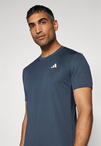 Camiseta de cuello redondo en color navy, hecha de un tejido suave, con mangas cortas y un pequeño logotipo blanco en la parte superior izquierda.