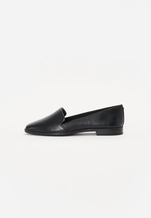 Zwarte leren platte schoenen met een spitse neus, uitsneden aan de zijkanten en een lage hak, met een gladde textuur en een minimalistisch ontwerp.