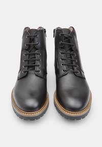 Czarne skórzane botki z teksturowaną powierzchnią, okrągłym noskiem i jasnobrązową podeszwą. Posiadają sznurowanie i zamek błyskawiczny do zapięcia.