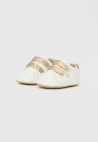 Λευκά βρεφικά παπούτσια με χρυσές λεπτομέρειες, διαθέτουν δύο λουριά με βέλκρο, στρογγυλεμένη μύτη και μαλακή σόλα. Ομαλή υφή με λεπτομέρεια λογότυπου στα λουριά.