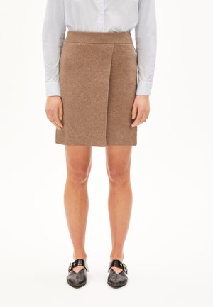 Gonna a lunghezza ginocchio in misto lana marrone, con una cintura a costine e dettagli a portafoglio; abbinata a scarpe basse nere e una camicia azzurro chiaro con bottoni.