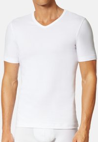T-shirt blanc à manches courtes avec un col en V, fabriqué en coton doux, forme ajustée, coutures minimales et sans logos visibles.