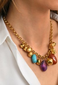 Collier en chaîne dorée avec des accents de pierres précieuses colorées : turquoise, rouge et violet. Textures lisses et brillantes avec des formes arrondies.