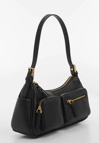 Sac à main en cuir noir à forme courbée, avec ferrures dorées, deux poches zippées sur le devant et une bandoulière réglable unique.