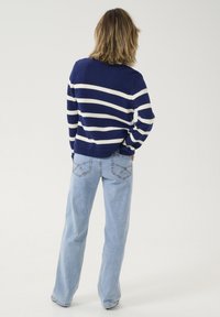 Navy and white striped knit sweater with a round neck, paired with light blue wide-leg jeans featuring stitched back pockets.